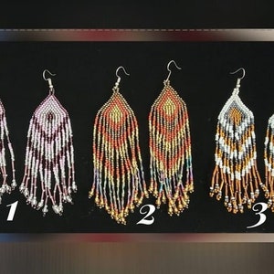May include: Three pairs of long, beaded earrings. The first pair is white and purple, the second pair is orange, gold, and purple, and the third pair is black, white, and gold. The earrings are labeled 1, 2, and 3.