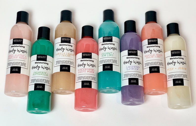 May include: Eight clear plastic bottles of body wash with black lids and white labels. The labels have the text "Moisturizing Body Wash" and the scent of each body wash. The scents are:  "Watermelon", "Vanilla & Coconut Cream", "Raspberry White Musk", "Coconut & Key Lime", "Lavender Oatmilk", "Tropical Fruit Sugar Cake", "Milk & Honey".