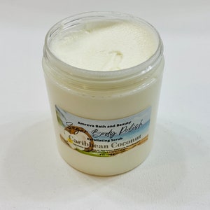 May include: A white jar of sugar body polish with a label that reads "Sugar Body Polish Exfoliating Scrub Caribbean Coconut" by Amreva Bath and Beauty.