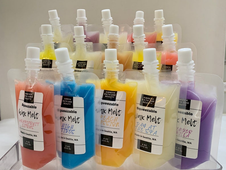 May include: An assortment of squeezeable wax melts in clear pouches, each with a white cap. The pouches contain colorful wax in shades of pink, blue, yellow, and purple. Each pouch has a label with the scent name and brand information.