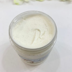 May include: A white jar of body butter with a white lid. The jar is filled with a white, creamy product. The jar has a label on the bottom that says "Sweet Pea and White Tea Body Butter".