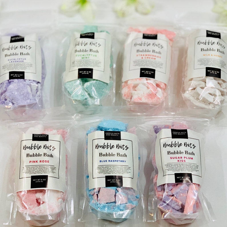 May include: Assortment of ten clear plastic bags containing bubble bath bits. Each bag has a white label with the text "Bubble Bits Bubble Bath" and a different scent. The scents are: Eucalyptus Lavender, Eucalyptus Mint, Strawberries & Cream, Milk & Honey, Pink Rose, Blue Raspberry, Sugar Plum Kiss.