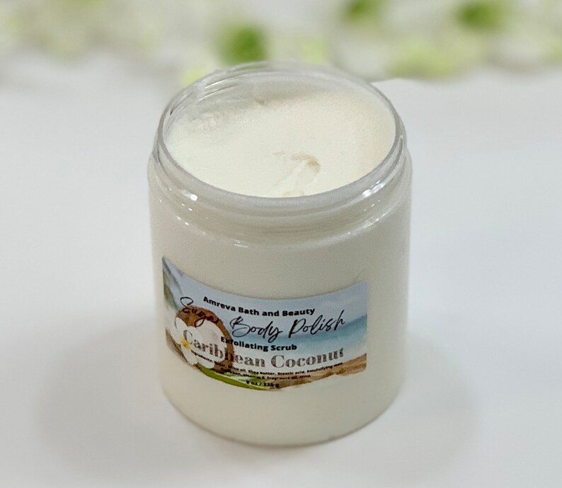 May include: A white jar of sugar body polish with a label that reads "Amreva Bath and Beauty Sugar Body Polish Exfoliating Scrub Caribbean Coconut 8 oz / 226g".