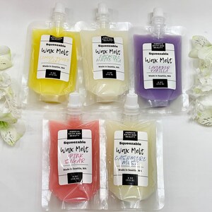 May include: An assortment of squeeze pouches filled with scented wax melts. The pouches are labeled with various scents, including Lemon Pound Cake, Jasmine White Tea, Lavender Vanilla, Pink Sugar, and Cashmere Mist. Each pouch contains 4 oz (113 g) of wax.