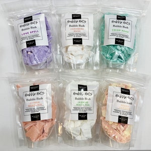 May include: Six clear plastic bags with white labels containing different bath bomb scents. The labels have the text "Bubble Bits" and the scent name. The scents are Love Spell, Cashmere Musk, Crisp Pear, Citron Mandarin, Jasmine White Tea, and Peach Passion.