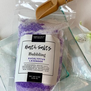 Pode incluir: Um saco de pl&aacute;stico transparente cheio de sais de banho roxos e brancos. O saco tem um r&oacute;tulo que diz "Bath Salts Bubbling Eucalyptus Lavender" e lista os ingredientes. O peso l&iacute;quido &eacute; de 8 oz (226 g).
