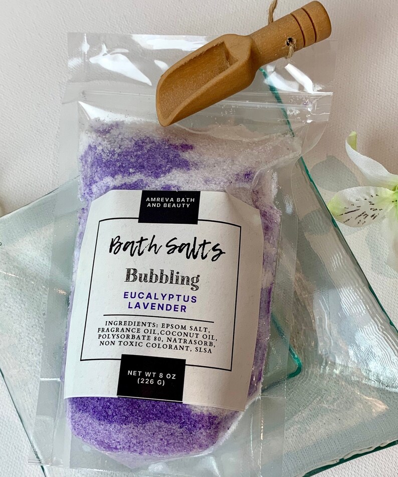 Pode incluir: Um saco de pl&aacute;stico transparente cheio de sais de banho roxos e brancos. O saco tem um r&oacute;tulo que diz "Bath Salts Bubbling Eucalyptus Lavender" e lista os ingredientes. O peso l&iacute;quido &eacute; de 8 oz (226 g).