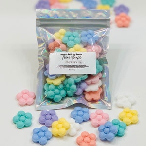 May include: A bag of small, colorful flower-shaped soaps. The bag is labeled "Amreva Bath and Beauty Mini Soaps Flowers".