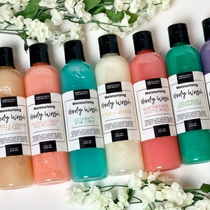 May include: Eight clear plastic bottles of body wash with black lids and white labels. The labels have the text "Moisturizing Body Wash" and the scent of each body wash. The scents are: "Sweet Water + Passion Fruit", "Vanilla & French Cream", "Tropical Fruit + Sugar Cane", "Coconut + Key Lime", "Milk + Honey", "Raspberry + White Musk", "Cacahuate + Watermelon", and "Lavender + Oatmilk".