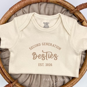 May include: A cream-colored baby onesie with brown text that reads "Second Generation Besties Est. 2026".