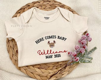 Body de bebé bordado con la frase "Here Comes" • Anuncio de embarazo navideño personalizado • Revelación de nacimiento del bebé en Navidad con fecha de parto • Body de reno