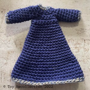 May include: A navy blue crocheted dress with a gold trim around the neckline and hem. The dress has long sleeves and a fitted bodice.