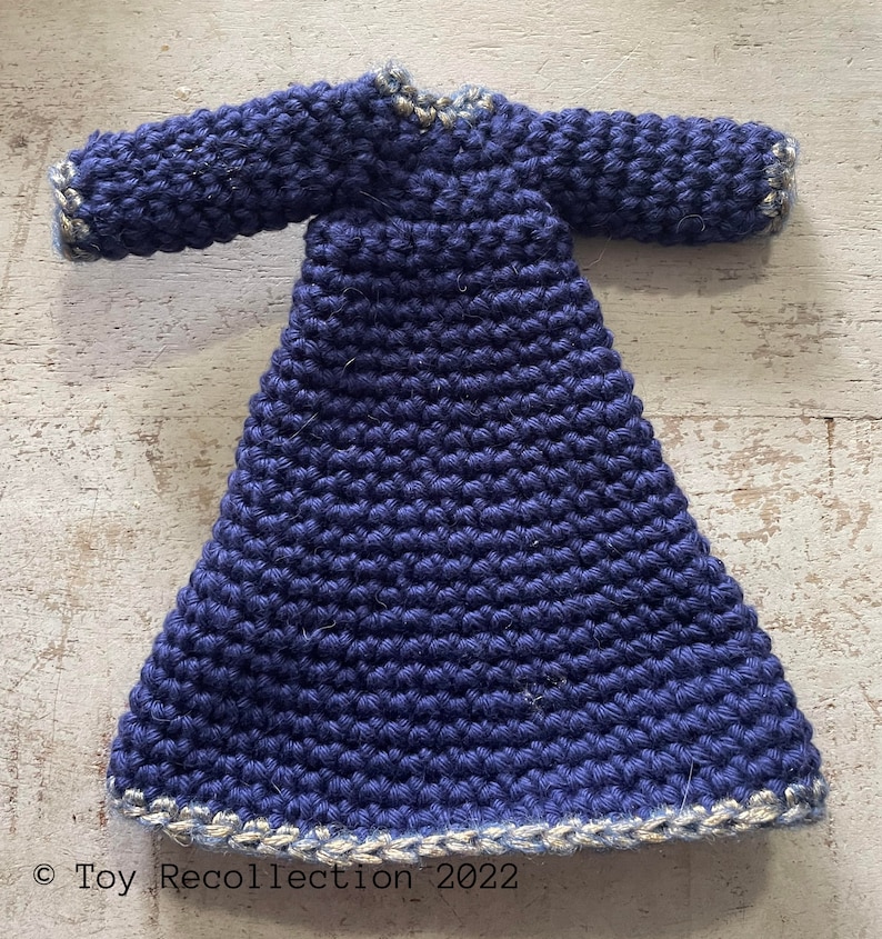 May include: A navy blue crocheted dress with a gold trim around the neckline and hem. The dress has long sleeves and a fitted bodice.