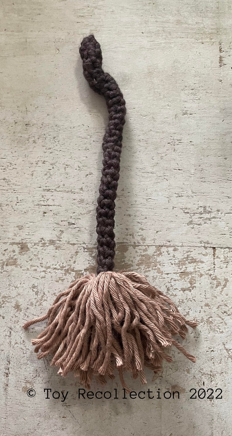 May include: A brown and beige crocheted tassel with a long, brown cord. The tassel is made of a soft, fluffy yarn and would be a great addition to a home decor project.