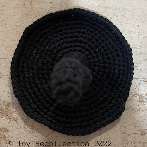 May include: Black crocheted witch hat with a pointed top. The hat is made using single crochet stitches and has a smooth, even texture.