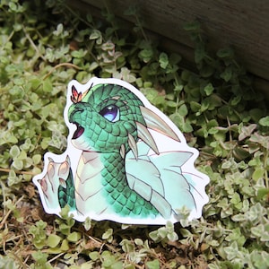 May include: A green and white dragon sticker with a butterfly on its head. The dragon has a light blue wing and is looking up.