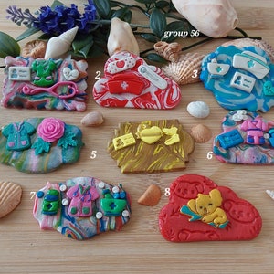 May include: Eight colorful handmade polymer clay charms with a medical theme. The charms are shaped like clouds, rectangles, and ovals. The charms feature various medical symbols, including a stethoscope, a bandage, a pill bottle, and a heart. The charms are labeled with numbers 1 through 8. The text "group 56" is visible in the top center of the image.