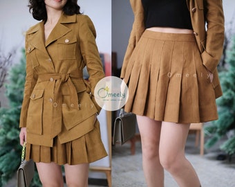May include: A mustard-brown jacket with a notched collar, long sleeves, four front pockets with button flaps, and a matching tie belt, paired with a matching mustard-brown pleated mini skirt. The text Omeely is visible on the garment.