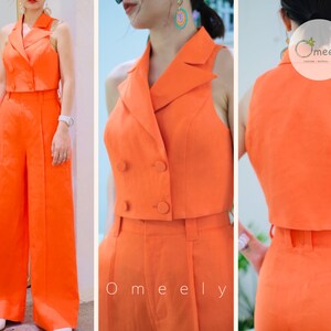 K&ouml;nnte beinhalten: Ein leuchtend orangefarbenes zweiteiliges Outfit mit einem kurzen Blazer-Oberteil und einer weiten Hose. Das Oberteil hat einen zweireihigen Verschluss und einen spitzen Kragen. Die Hose hat eine gerade Beinlinie und eine hohe Taille.