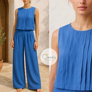 May include: A bright blue sleeveless jumpsuit featuring a round neckline and vertical pleats on the bodice. The garment includes wide-leg trousers and a cropped overlay top. A circular logo with the text Omeely is visible on the lower right side.