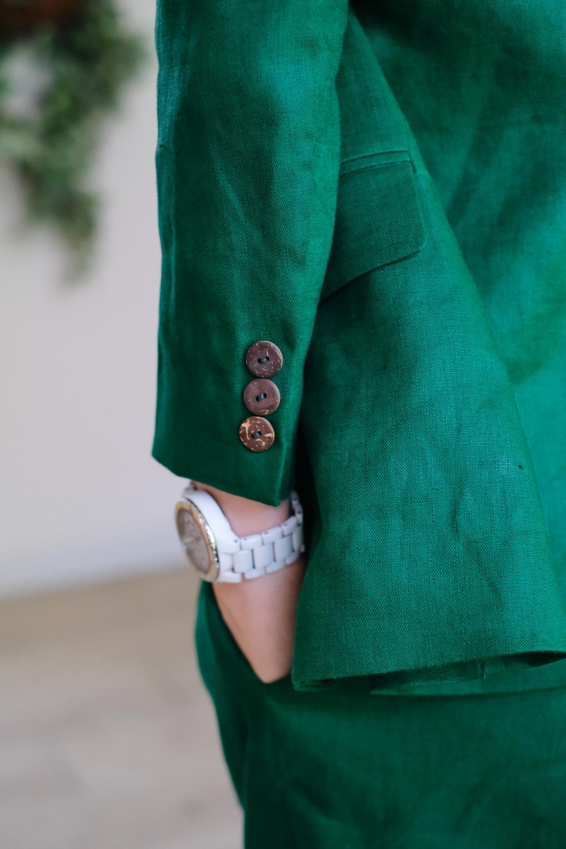May include: A green linen blazer with three brown coconut shell buttons on the sleeve.