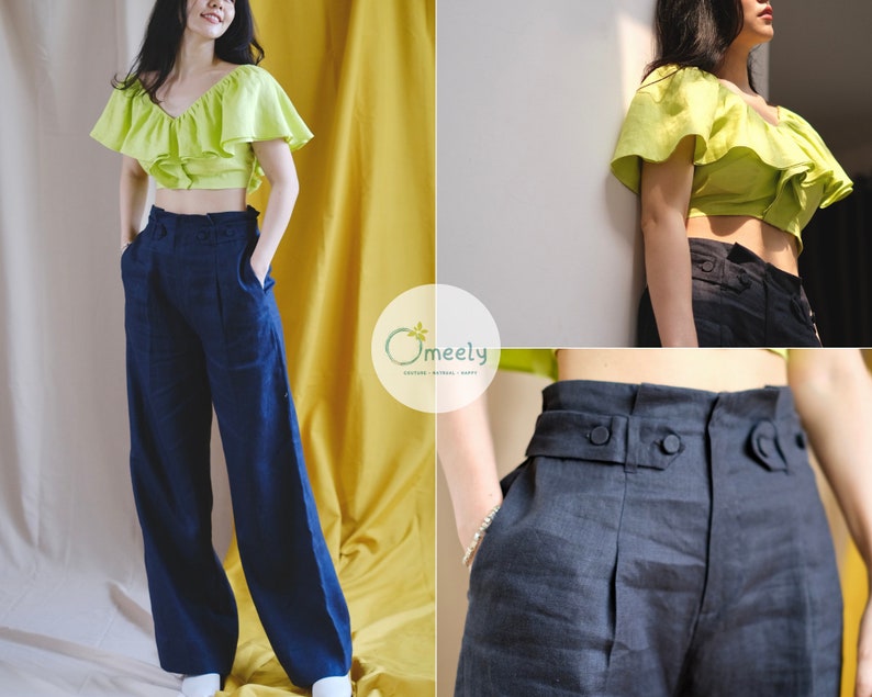 May include: A woman is wearing a lime green ruffled crop top and dark blue wide-leg pants with a high waist. The pants have a button closure and a belt loop. The woman is standing in front of a yellow wall.