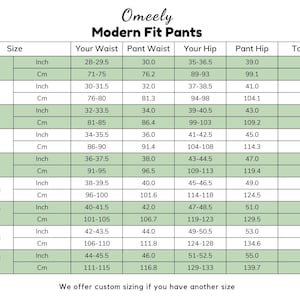 Op de afbeelding: Een maattabel voor Omeely Modern Fit broeken met kolommen voor maat, taille, heup en totale stijging in inches en centimeters. De tabel bevat maten van 28 (XS) tot 44 (5XL) met specifieke numerieke gegevens.