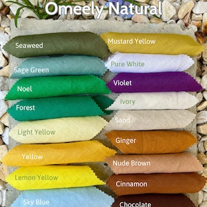 May include: A display of linen fabric swatches in various colors, including green, yellow, and brown. The swatches are labeled with color names like "Seaweed," "Mustard Yellow," and "Chocolate." The text "Omeely Natural" is at the top, and "100% Linen 150gsm" is at the bottom.