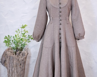 Könnte beinhalten: Ein beigefarbenes, bodenlanges Mantelkleid mit langen Ärmeln, hohem Stehkragen mit Rüschen, durchgehender Knopfleiste mit Metallknöpfen, tailliertem Schnitt mit Gürtelschlaufen und zwei großen aufgesetzten Taschen am ausgestellten Rockteil.
