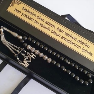 Peut inclure: Un ensemble de chapelet noir avec des accents argentés et un charme en forme de cœur. Les perles sont dans une boîte noire avec une inscription dorée qui dit "Nefesim olan adam, ben varken ellerim ben yokken bu tesbih olsun avuçlarının içinde."