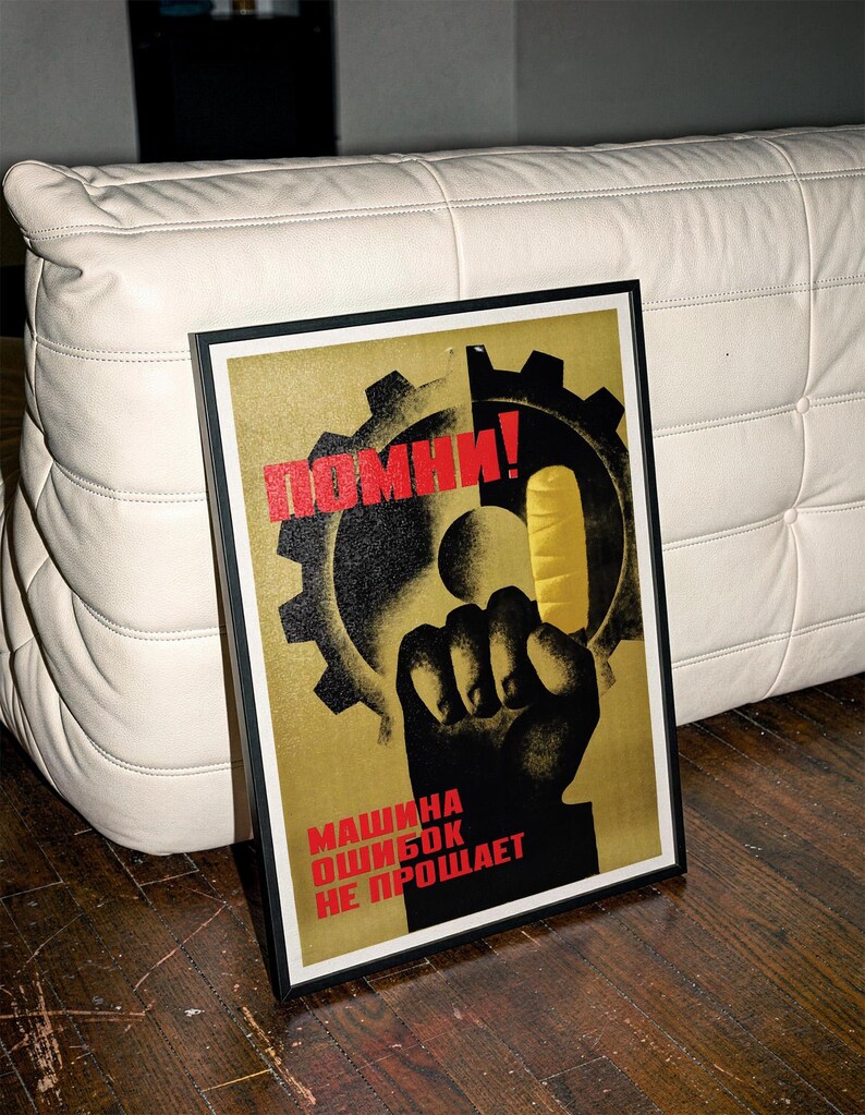 Pu&ograve; includere: Un poster incorniciato con la sagoma nera di un pugno rivolto verso l'alto contro un grande ingranaggio e una forma gialla. Il testo "ПОМНИ!" &egrave; in rosso in alto e "МАШИНА ОШИБОК НЕ ПРОЩАЕТ" in rosso in basso su uno sfondo dorato testurizzato.