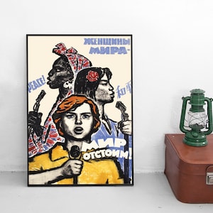 May include: A framed poster featuring a stylised illustration of three diverse individuals speaking into microphones. The artwork includes Cyrillic text, the word PEACE, and Chinese characters, set against a cream background with bold yellow, blue, and red accents.
