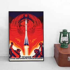 May include: A vintage Soviet propaganda poster featuring a rocket launching into space. The poster is red, orange, and blue with a large red star and the text "TRUDOM KRIPI MOGUTNIST BAT'KIVSHYNI!" which translates to "By labor we strengthen the power of our Motherland!"
