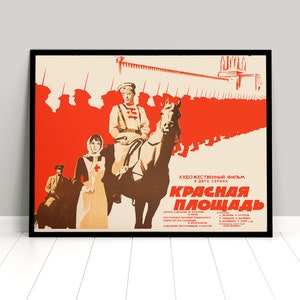 May include: A vintage film poster for the movie "Красная Площадь" (Red Square) in two parts. The poster features a red background with a line of soldiers marching in silhouette. A woman in a white dress and a man on horseback are in the foreground. The poster is framed in black.
