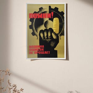 Pu&ograve; includere: Un poster rettangolare con sfondo giallo che presenta la sagoma nera di un ingranaggio e un pugno rivolto verso l'alto. L'indice del pugno ha una benda gialla. Il testo rosso recita "ПОМНИ!" in alto e "МАШИНА ОШИБОК НЕ ПРОЩАЕТ" in basso.