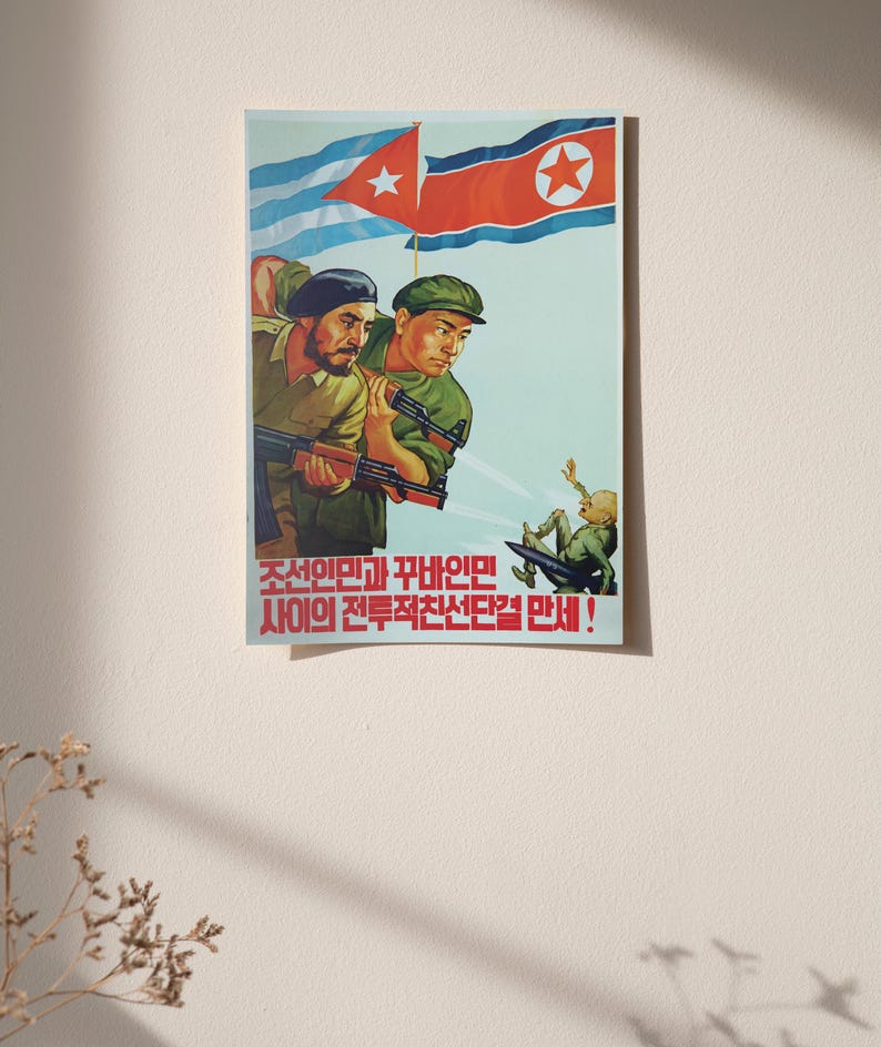 K&ouml;nnte beinhalten: Ein Propagandaposter mit zwei Soldaten in gr&uuml;nen Uniformen, die Gewehre halten und unter den Flaggen von Kuba und Nordkorea stehen. Eine kleine Figur ist darunter fallend dargestellt. Roter koreanischer Text steht am unteren Rand des Posters.