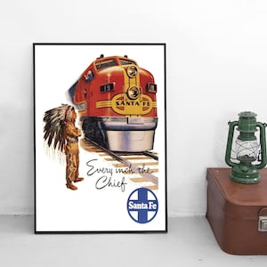 May include: A framed vintage-style poster featuring a red and yellow Santa Fe locomotive train on tracks, a person in a traditional feathered headdress, the text Every inch the Chief, and a blue and white circular Santa Fe logo on a white background.