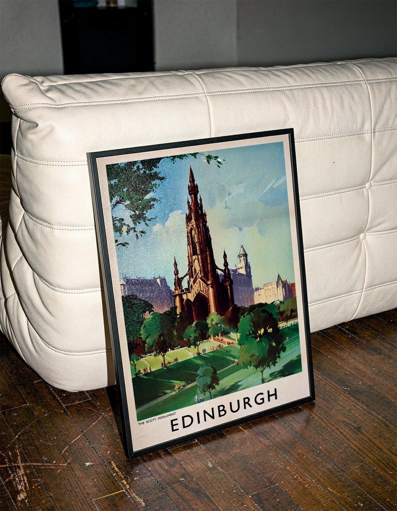 May include: A framed travel poster featuring a dark, detailed illustration of the Scott Monument in Edinburgh, Scotland. The artwork displays a green park in the foreground, blue sky, and the text THE SCOTT MONUMENT and EDINBURGH at the bottom.