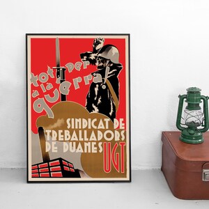 May include: A framed vintage propaganda poster featuring a soldier in a helmet with a raised fist and a bayonet against a red background. The text reads 'tot per a la guerra!' and 'SINDICAT DE TREBALLADORS DE DUANES UGT' above a factory silhouette.