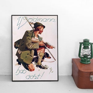Op de afbeelding: Een vintage poster met een jager in een groene jas en hoed die een geweer vasthoudt. De poster heeft de tekst "Weidmann, hab acht!" in het Duits.