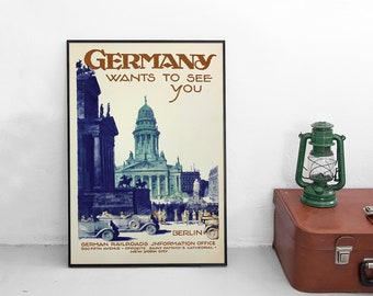 May include: A vintage travel poster titled GERMANY WANTS TO SEE YOU, featuring a blue-toned illustration of the Gendarmenmarkt in Berlin with classic cars, text at the bottom detailing the German Railroads Information Office in New York City.