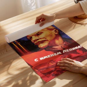 May include: A vintage Soviet propaganda poster featuring a portrait of Lenin with the text "С именем Ленина!" (With the name of Lenin!). The poster is red, white, and blue with a star in the background.