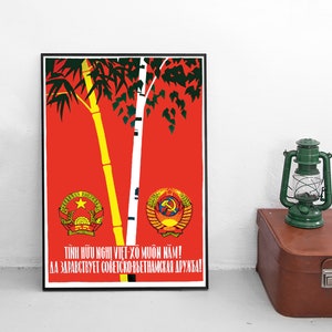 Op de afbeelding: Een rode en gele poster met een groene bamboeplant en een witte berk. De poster heeft de tekst "TÌNH HỮU NGHỊ VIỆT XÔ MUÔN NĂM! ДА ЗДРАВСТВУЕТ СОВЕТСКО-ВЬЕТНАМСКАЯ ДРУЖБА!" in zwart.