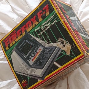 Grandstand, &quot;Firefox F-7&quot;, &quot;Astro Thunder&quot;, boxed, LSI, VFD handheld game console, 80s retro collectors item, backlit screen, Tandy, Epoch