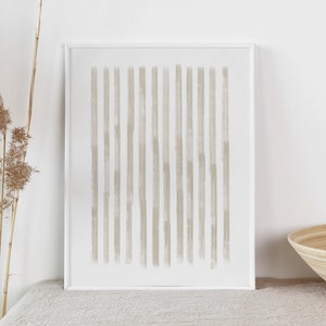 Op de afbeelding: Een ingelijst print met een minimalistisch ontwerp met een reeks verticale, lichtbruine penseelstreken op een witte achtergrond.