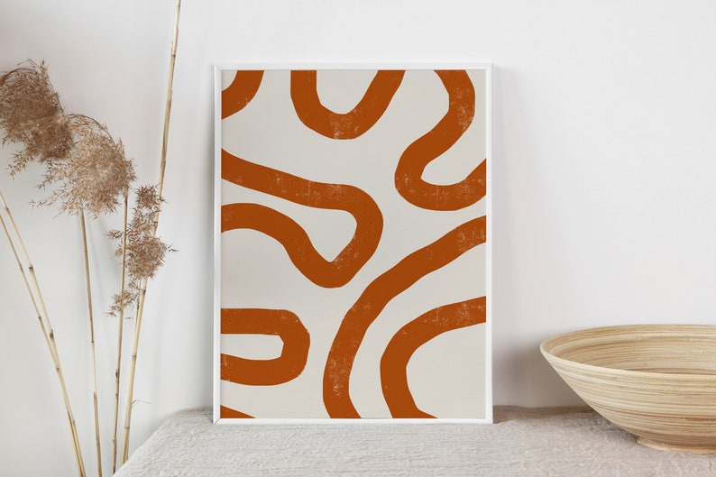 Peut inclure: Impression d'art abstrait avec un fond blanc et des lignes courbes textur&eacute;es de couleur rouille. L'&oelig;uvre est encadr&eacute;e dans un cadre blanc et expos&eacute;e sur une surface aux tons neutres. L'esth&eacute;tique g&eacute;n&eacute;rale est minimaliste et moderne.