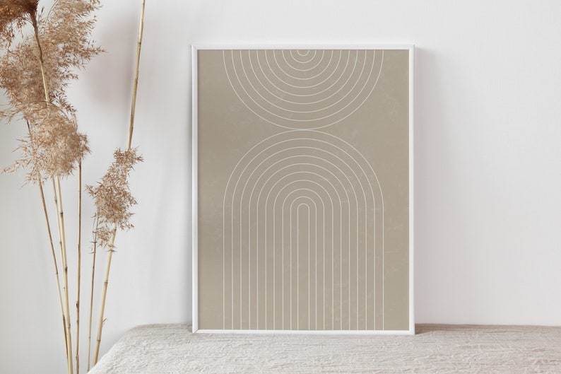 Op de afbeelding: Een ingelijst print met een beige achtergrond en witte geometrische vormen. De vormen zijn een reeks concentrische cirkels en bogen.