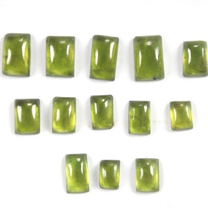 May include: Thirteen green gemstone cabochons in a rectangular shape, arranged in three rows on a white background.