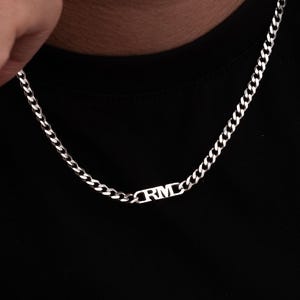 May include: A silver curb chain necklace with a small silver pendant that says "RMD".