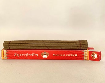 May include: A box of brown incense sticks with a red label that says "MONLAM INCENSE" and Tibetan text. The box is open and the sticks are visible.